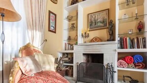 A traditional room with a fireplace, bookshelves, and a bed with a red and white patterned bedspread. - Belvilla by OYO Villa Valencina de la Concepcion (Valencina de la Concepcion)