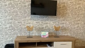 Ett TV-bord i trä med två dekorationer formade som fjärilar, en platt-TV monterad ovanför och en liten låda placerad på bordet.