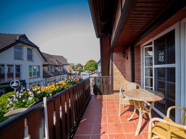 A balcony with a tiled floor, a table, and two chairs. - Holiday Apartment Lutt Matten (Zingst)