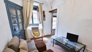 A living room with a sofa, armchair, ottoman, and a glass table with a television. - Villa a Palafrugell con Spiaggia di Mare (Palafrugell)
