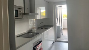 A modern kitchen with white cabinets, a stainless steel microwave, and a built-in oven. - Belvilla by OYO Apartamento Port Avenue (Marbella)