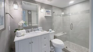 A modern bathroom with a glass shower enclosure, a white sink with a mirror above, and a toilet with a glass partition. - 862 Ketch Court at The Sea Pines Resort (Hilton Head Island)