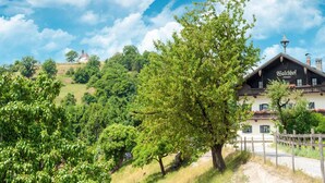 Un edificio tradicional con un letrero que dice "Balkhof" en un paisaje verde y exuberante, con cielo despejado.