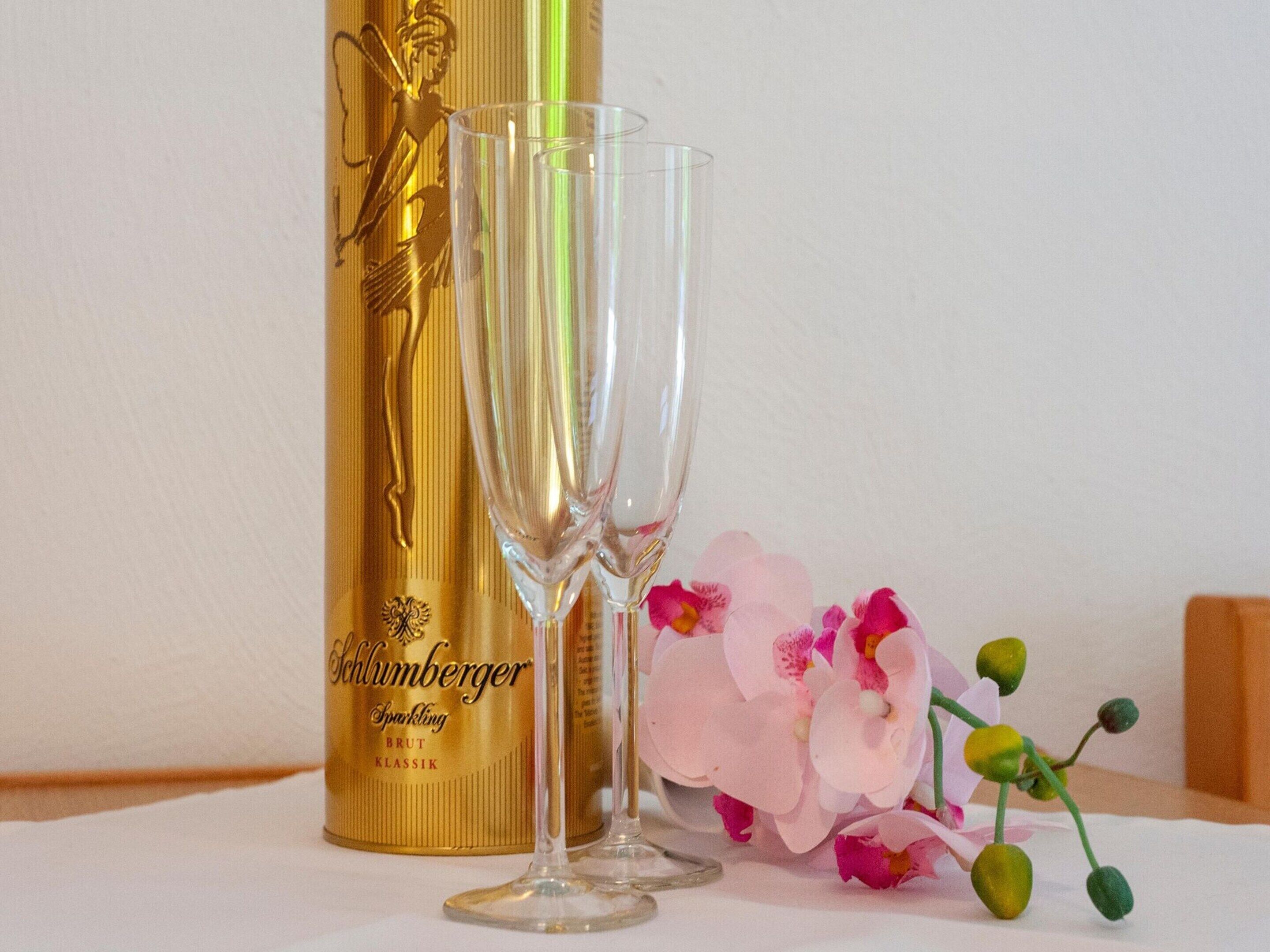 Two champagne flutes in front of a golden bottle with a label.
