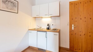 Una cocina compacta con armarios blancos, una encimera de madera, una cafetera y un lavamanos.