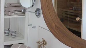 Un baño con tocador blanco, un espejo redondo y una puerta de madera.