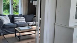 Ένα σαλόνι με έναν καναπέ, ένα τραπεζάκι σαλονιού και ένα φωτιστικό οροφής.