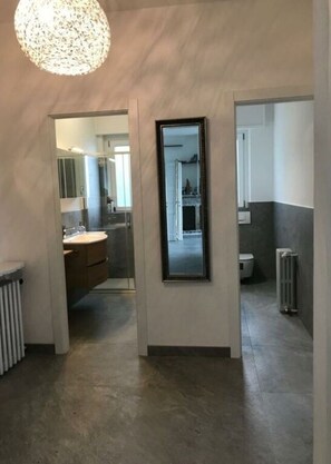A modern bathroom with a large mirror, a toilet, and a radiator.