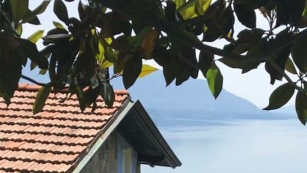 A stone building with a red-tiled roof, a balcony, and a view of a body of water. - Majestic Apartment in Trarego-viggiona (Trarego Viggiona)