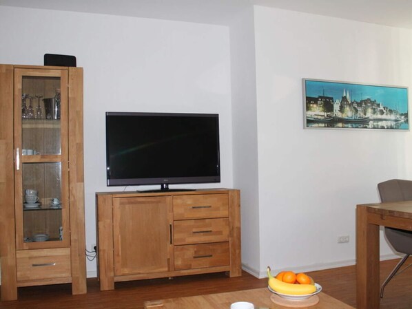 Relax in this inviting living room with a flat-screen TV, glass-fronted cabinet, and a beautiful cityscape painting.