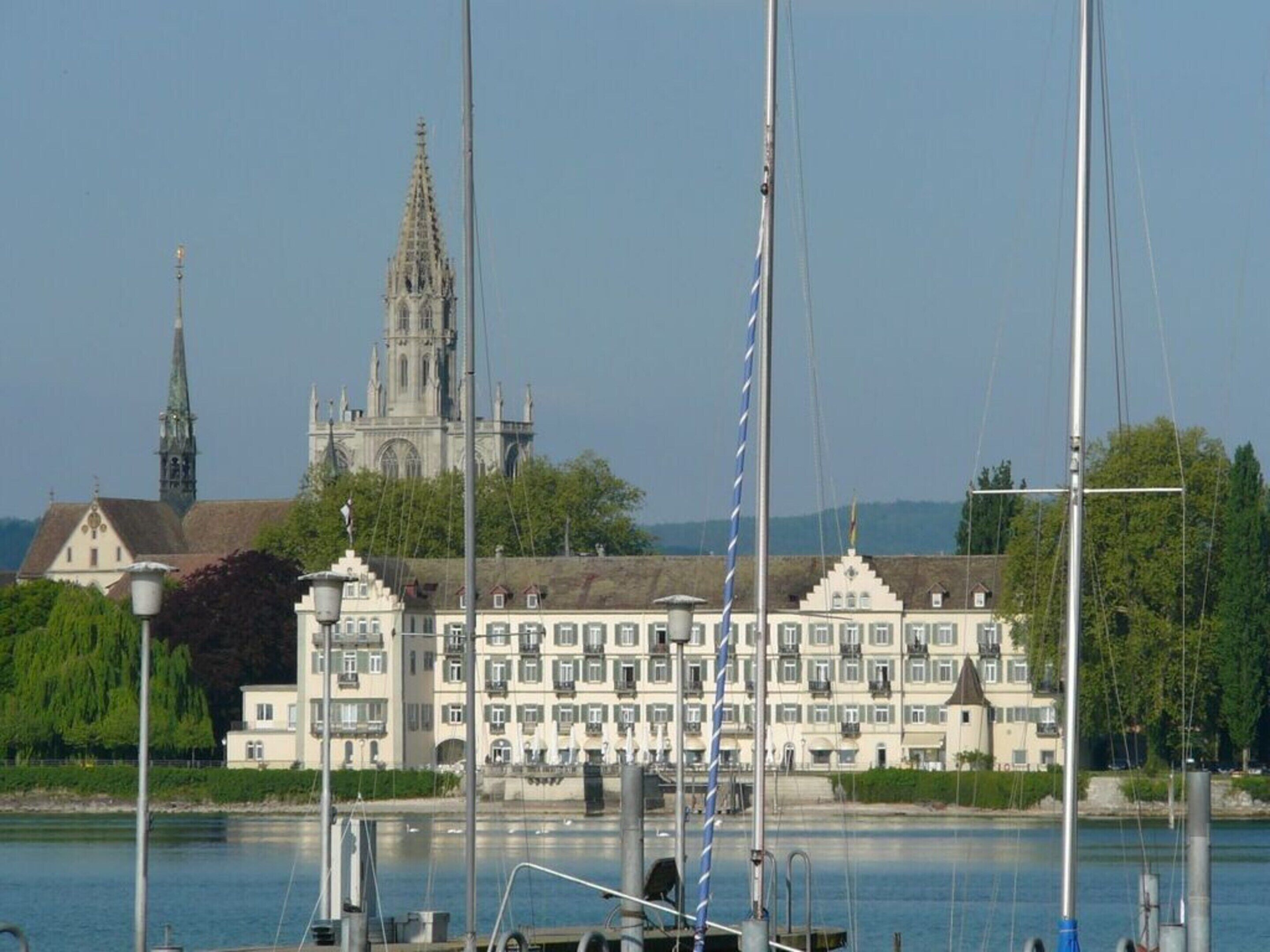 A waterfront hotel with a large building featuring multiple balconies and a church in the background.