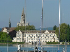 A waterfront hotel with a large building featuring multiple balconies and a church in the background. - Holiday Apartment Seeloft (Konstanz)