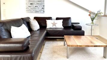 A modern living room with a sectional sofa, a coffee table, and a wall-mounted abstract art piece.