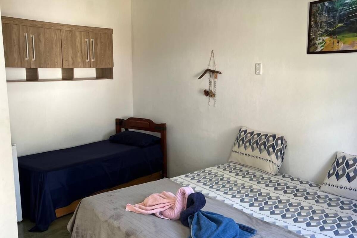 Un dormitorio con una cama, una cama individual, un armario, un ventilador de techo y una obra de arte colgada en la pared.
