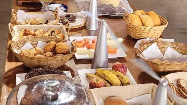 A breakfast buffet with various pastries, fruits, and a coffee station. - Pousada Sempre Viva  (São João Batista do Glória)