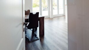 A spacious room with large windows, a dining table, and a dark wooden floor. - Loheide Modern Retreat (Langenhorn)