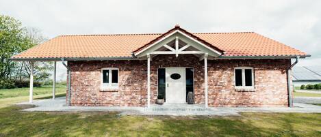A single-story brick house with a red-tiled roof, a front porch, and a small front yard.