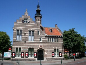 A historic building with a prominent tower and a red-tiled roof. - Huijsmansverhuur Type C Comfort Plus Prinsenhof 51 (Ouddorp)