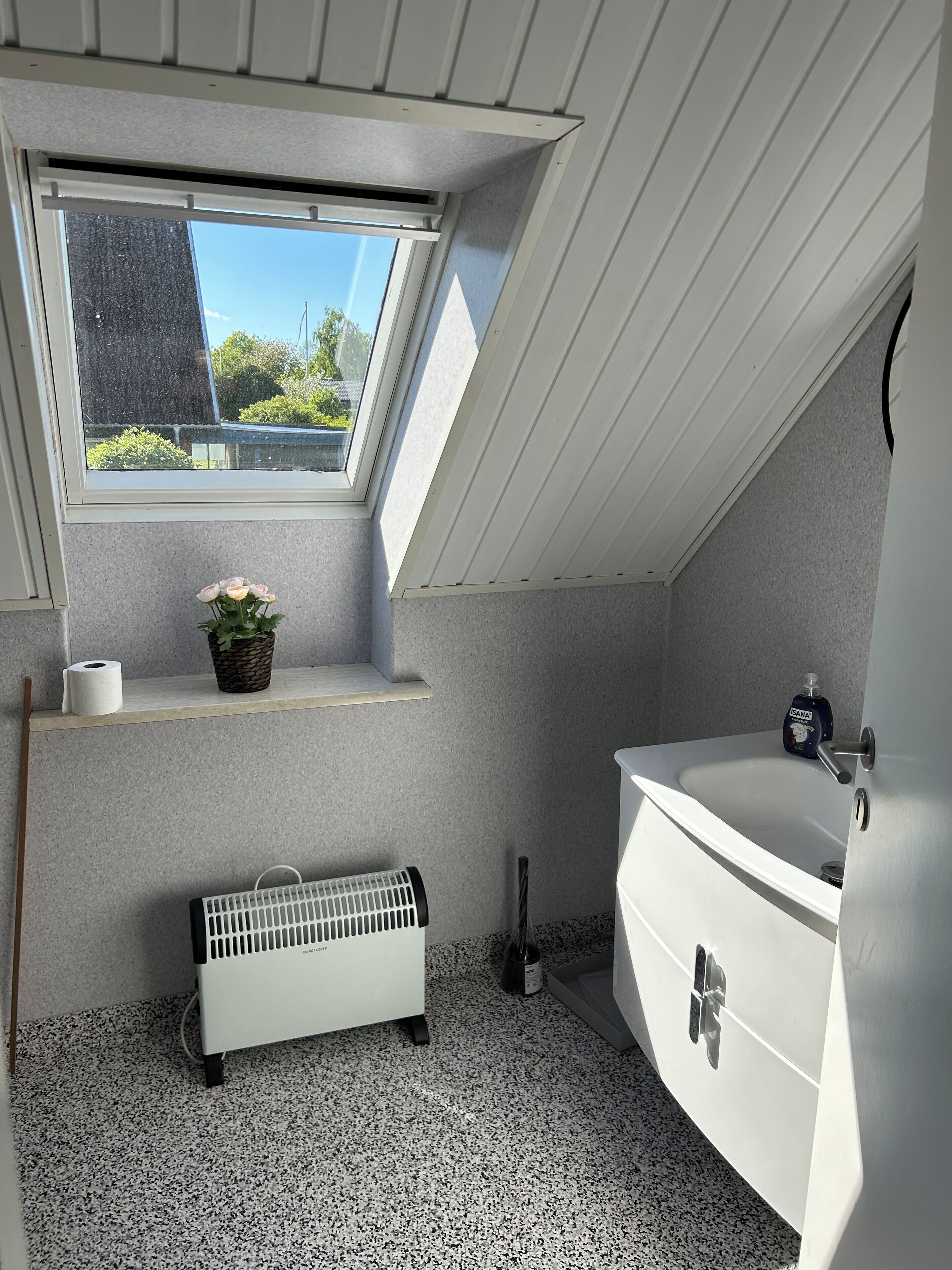 Une petite salle de bain moderne avec un puits de lumière, un radiateur blanc, un lavabo et des toilettes.