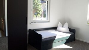 A compact bedroom with a bed, a window, and a door.