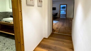 A hallway with wooden flooring, a sink, and two framed pictures on the wall.