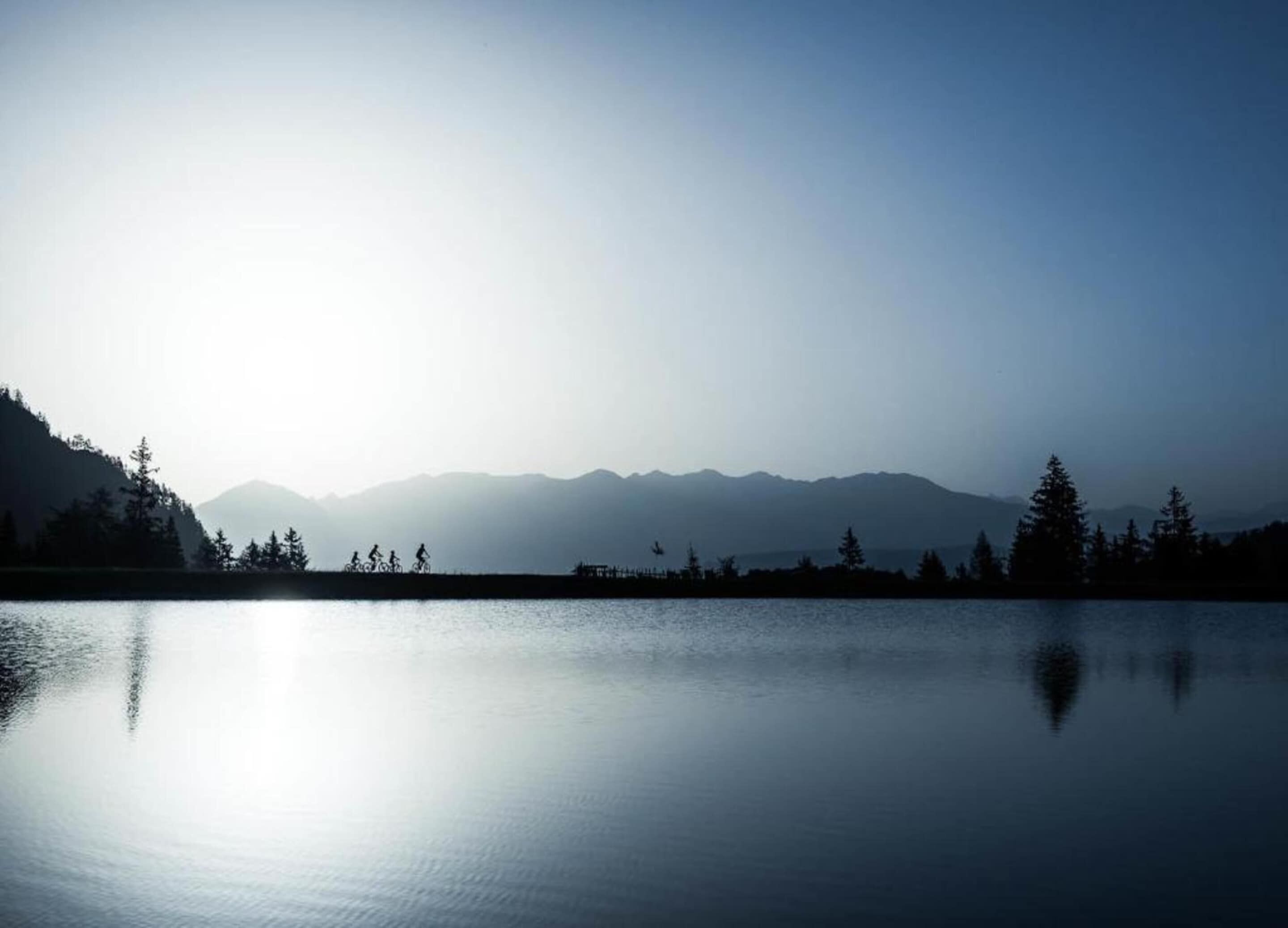 Un lago tranquilo con montañas al fondo y un cielo despejado.
