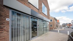A modern building with large glass doors, a brick facade, and a clear sky. - Beautiful Holiday Home Near sea in Katwijk (Katwijk Aan Zee)