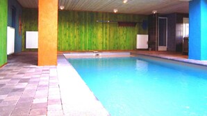 Une piscine intérieure avec un sol carrelé et un plafond en bois.