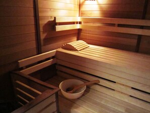 Eine Sauna mit Holzbänken und einer Holzschüssel mit Holzlöffel.