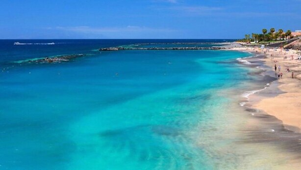A beach with clear turquoise water, a sandy shore, and a pier extending into the sea. - Belvilla by OYO Apartamento en Playa Las Carmenes (San Cristóbal de La Laguna)