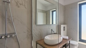 Un baño moderno con un espejo grande, un lavabo blanco y una ducha.