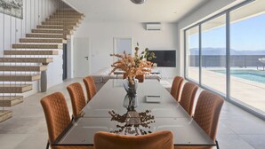 Un comedor moderno con una mesa larga, sillas tapizadas en naranja y un jarrón con flores.
