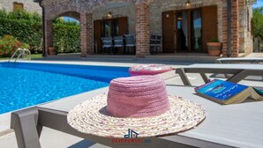 A poolside area with a woven hat and a book on a lounge chair. - Villa Amani Comfortable Holiday Residence (Svetvincenat)
