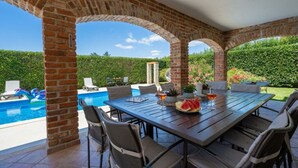 An outdoor patio with a pool, brick arches, and a table set for dining. - Villa Amani Comfortable Holiday Residence (Svetvincenat)