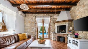 A cozy living room with a stone wall, a leather sofa, a white coffee table, and a fireplace. - Villa Amani Comfortable Holiday Residence (Svetvincenat)