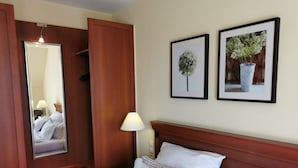 Ein Hotelzimmer mit Bett, Nachttisch, Lampe, Spiegel und zwei gerahmten Bildern an der Wand.