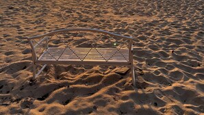 Una playa con un banco de metal en primer plano.