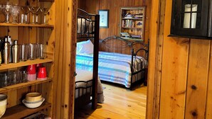 Un interior de madera con una cama, estanterías con cristalería y una biblioteca.