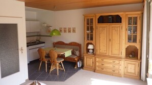A compact kitchen with a dining area, wooden cabinets, and a green pendant light. - Holiday Apartment Biermann (Schluchsee)