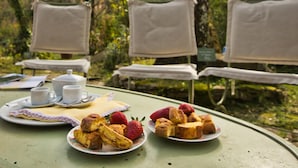 A table set outdoors with plates of food, a teapot, and two chairs. - Holiday Home in Sassetta Near Beaches (Castagneto Carducci)
