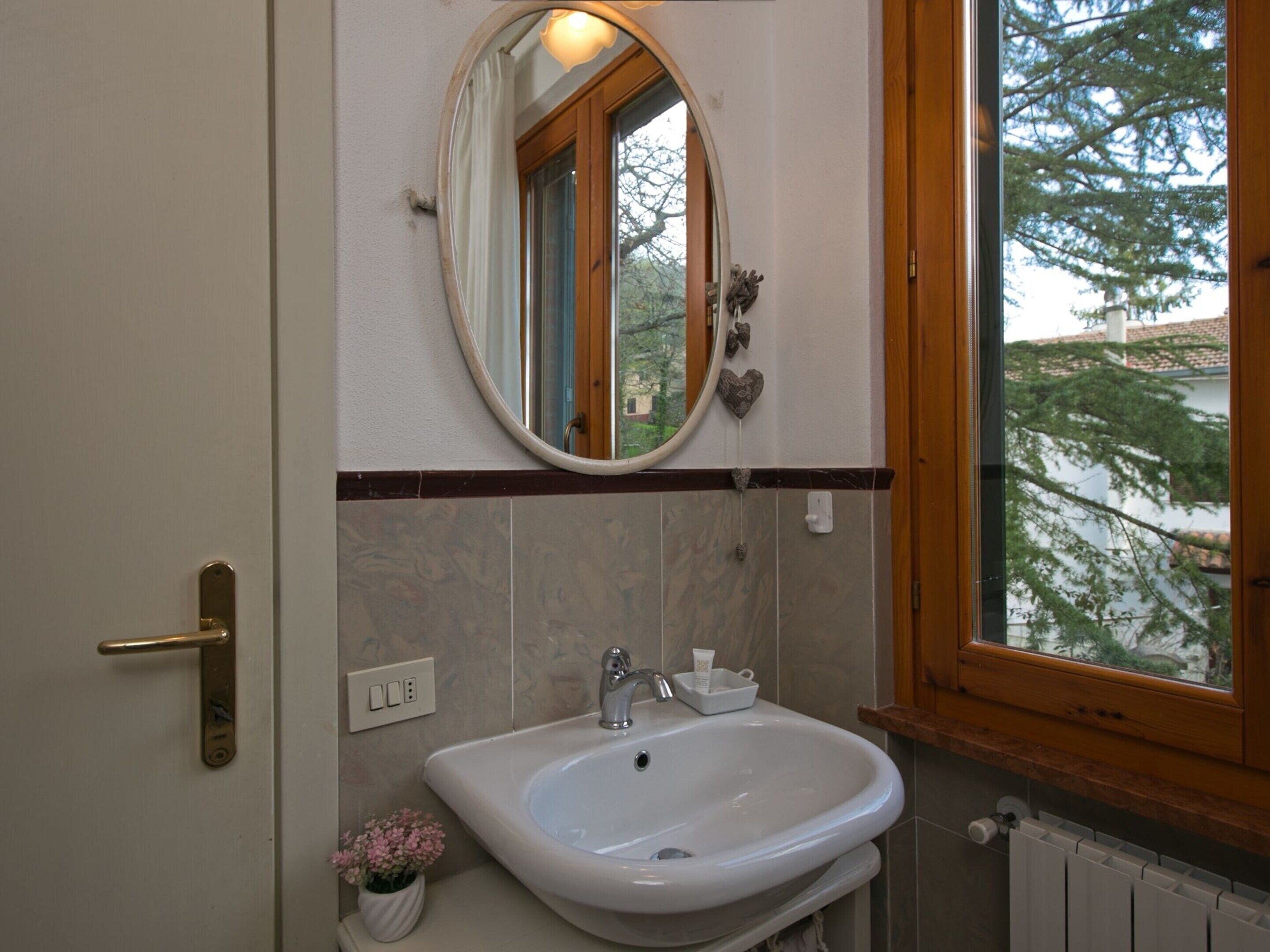 Un bany amb un lavabo blanc, un mirall i una finestra.