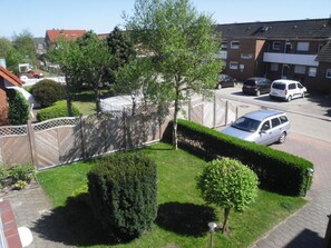 Un barrio residencial con un césped cuidado, un seto y un coche aparcado.