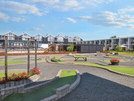 Ein Spielplatz mit einer Kletterkonstruktion, einem kleinen Pool und einer Sitzgelegenheit mit Tisch und Stühlen.