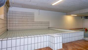 Una piscina con azulejos, suelo y paredes revestidas, rodeada de una zona de solárium con pavimento de azulejos.
