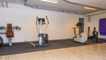 Een fitnessruimte met cardioapparaten, een hometrainer en een roeimachine.