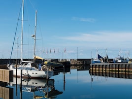 Un puerto deportivo con barcos amarrados, un muelle de madera y un cielo despejado.