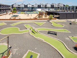 Un parque infantil con un arenero, columpios y un tobogán.