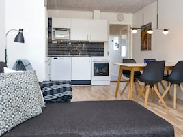 Una cocina moderna con armarios blancos, microondas y horno. Hay una zona de comedor con una mesa de madera y sillas negras.