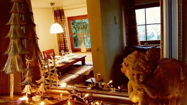 Un coin repas avec une table dressée pour deux personnes, un sapin de Noël et une statue.