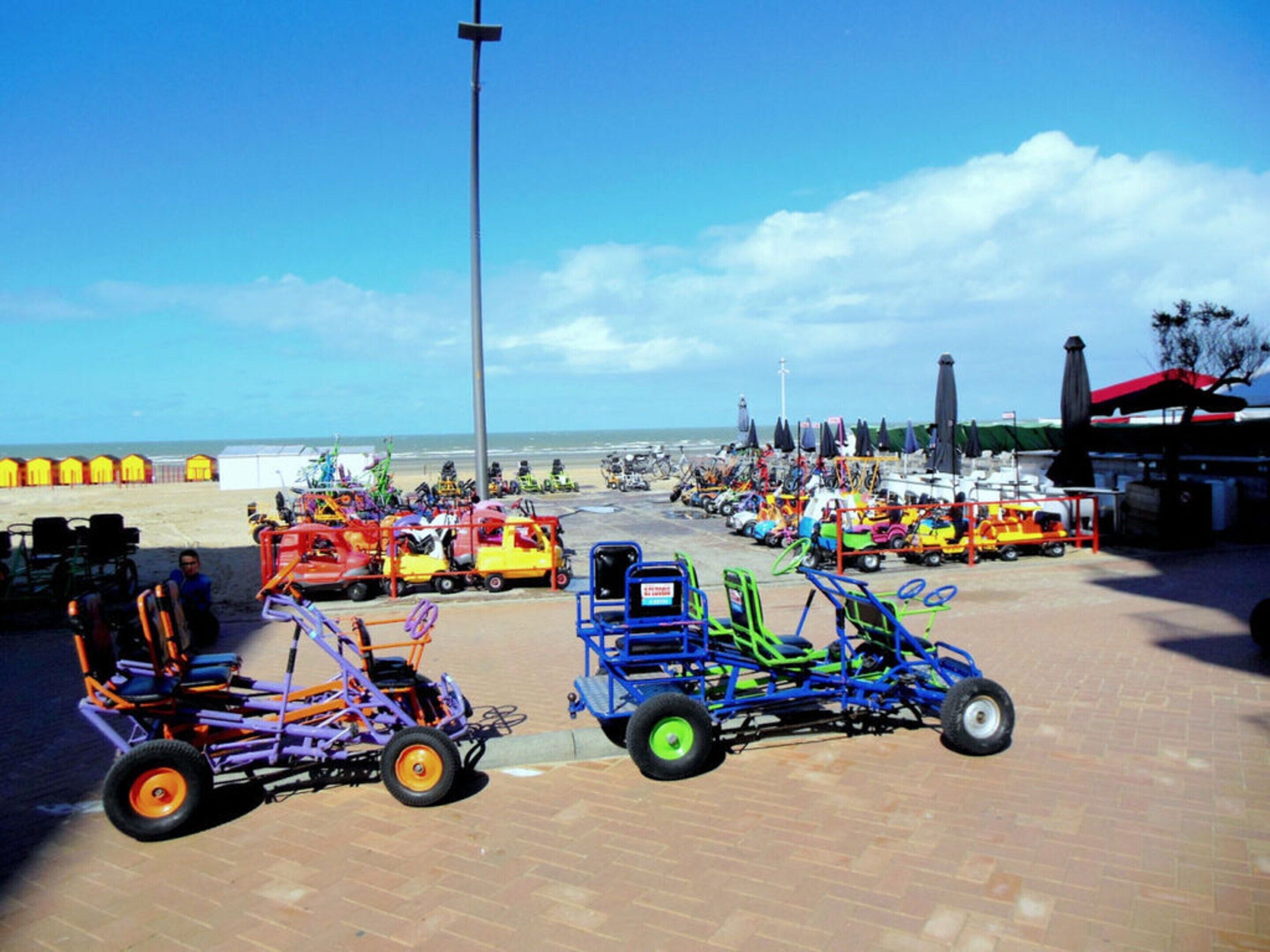 A beachside parking lot with various colorful vehicles and beach chairs.